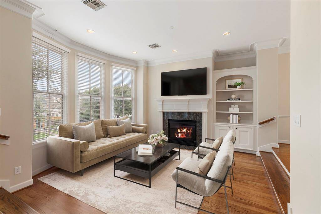 Charming family room with virtual staging, featuring a cozy fireplace, elegant built-ins, and abundant natural light.