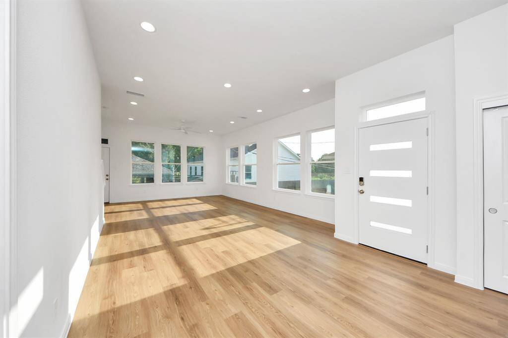 The living room is a bright, airy space, featuring large windows that flood the area with natural lights and vinyl flooring.