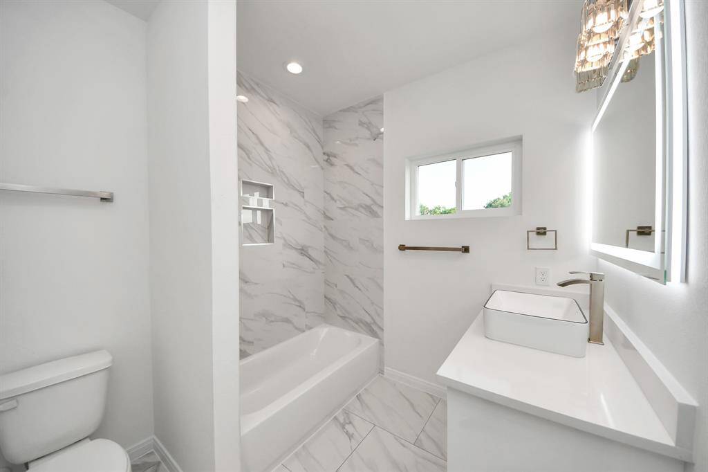The second bathroom has a shower -tub combo featuring LED lights and ceramic tile surround, adding a clean and polished look.