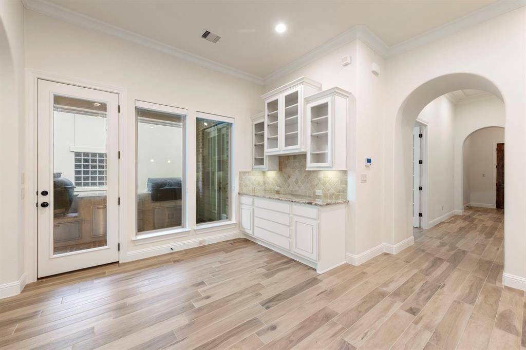 Just off the kitchen, this charming breakfast nook features a built-in buffet with glass-front cabinetry and direct access to the outdoor kitchen—blending functionality with seamless entertaining.