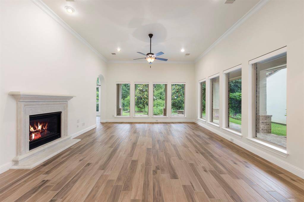 A true showstopper, the living room combines warmth and grandeur with its elegant gaslog fireplace, crown molding, and a full wall of windows showcasing the unmatched privacy of the wooded backyard. This photo has been virtually staged.