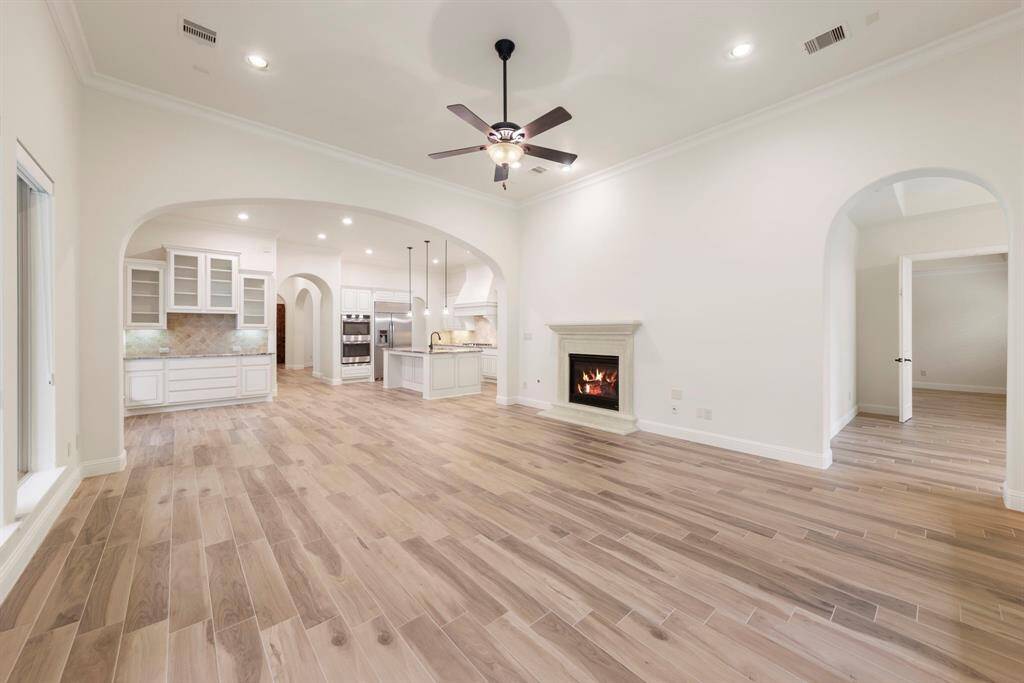 Designed for effortless flow and elevated living, this spacious family room blends indoor comfort with views of the private outdoor kitchen, highlighted by a cozy fireplace and wall-to-wall windows. This photo has been virtually staged.