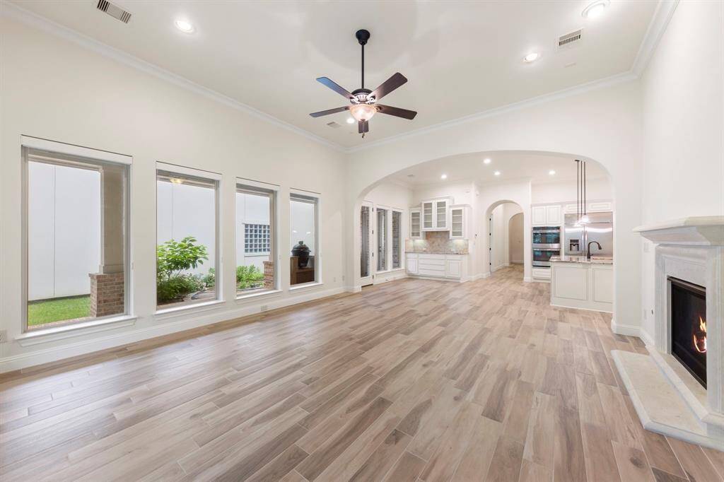 Framed by elegant archways, this wide-open living space blends the warmth of a gaslog fireplace with seamless flow into the kitchen and breakfast area—perfect for everyday comfort and elevated entertaining.