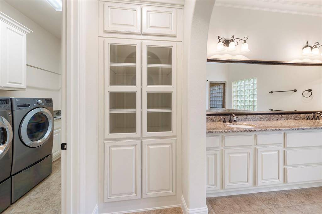 The primary bath features dual sinks with granite counters, elegant built-in storage, and direct access to the laundry room—designed for everyday ease and luxury living.