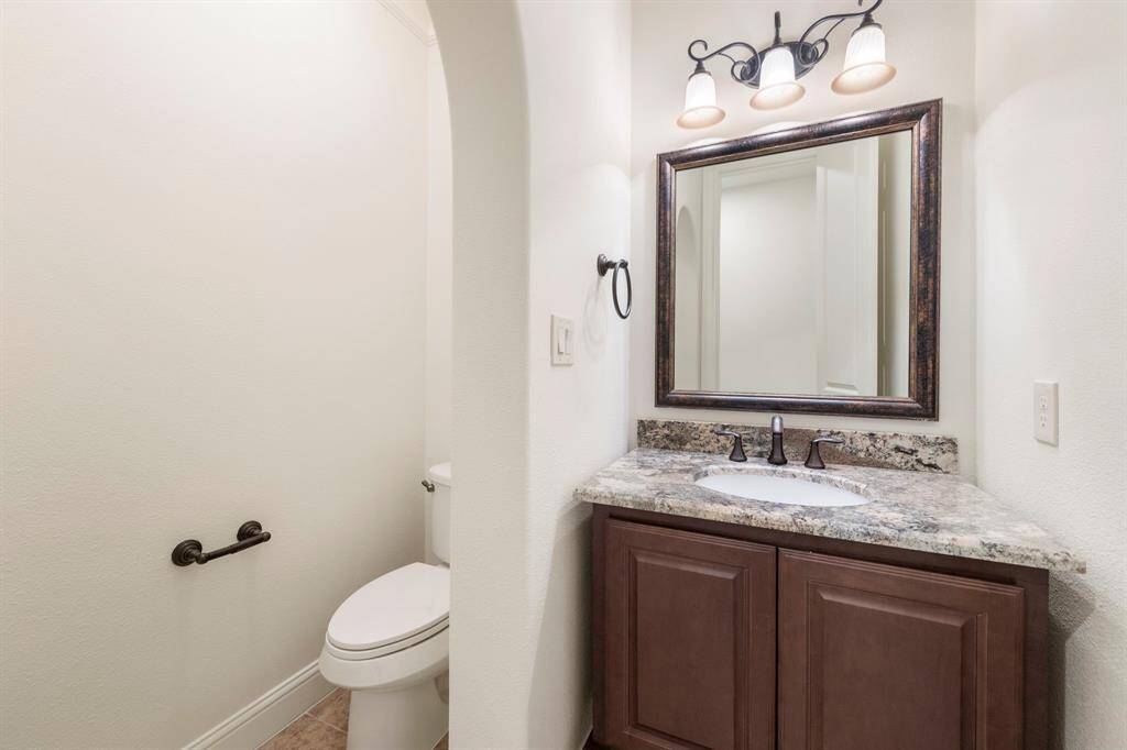 The powder bath offers timeless charm with rich cabinetry, granite counters, and bronze fixtures—perfectly placed for guest use.
