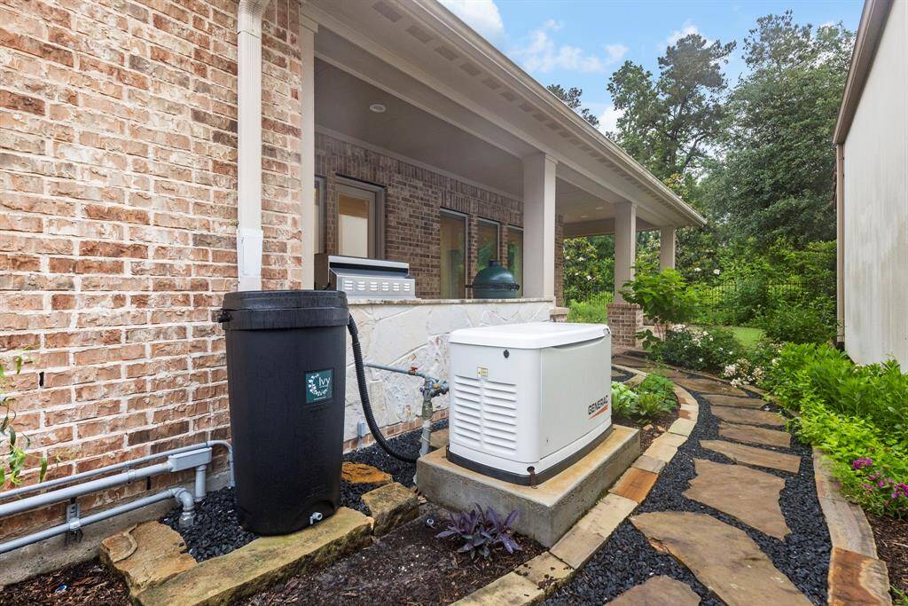This home is equipped with a whole-house Generac generator and rainwater collection system, nestled along a professionally landscaped stone pathway.