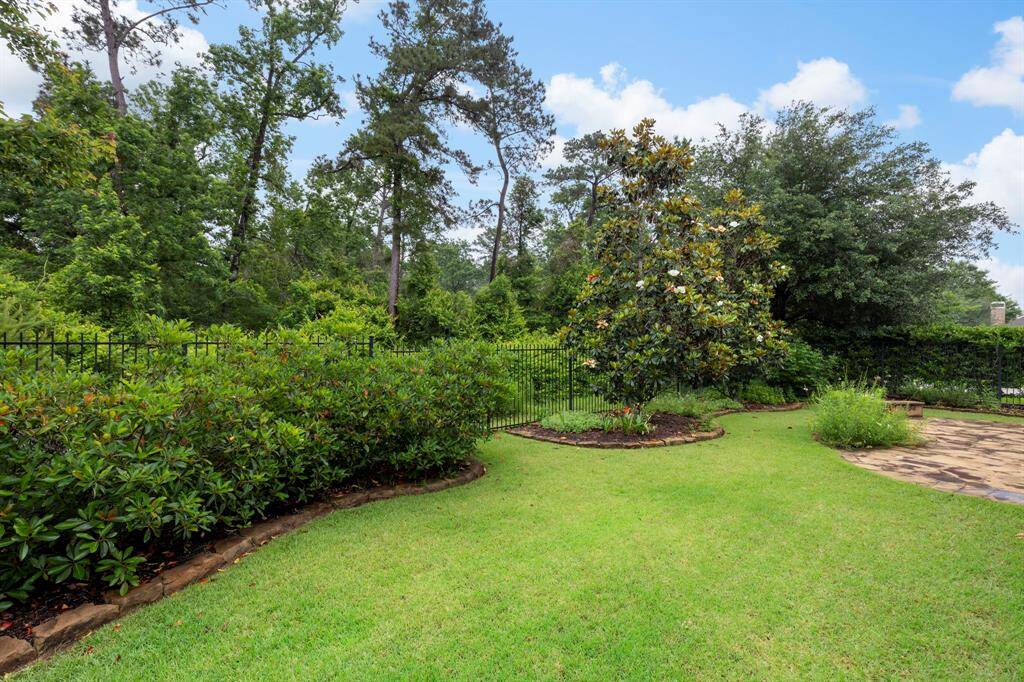 This beautifully landscaped backyard offers lush greenery, flowering magnolias, and a stone patio perfect for outdoor entertaining or peaceful nature views.