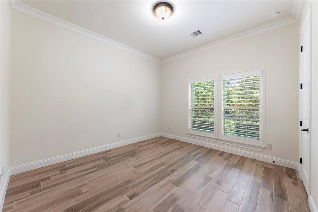At the front of the home, two secondary bedrooms feature crown molding, plantation shutters, and generous closets.