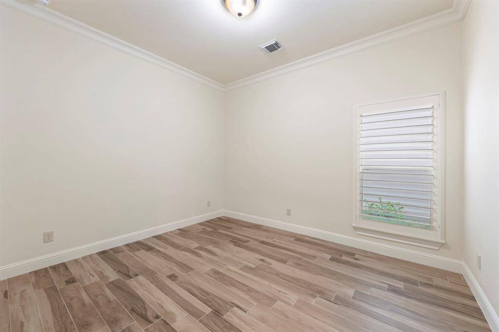 At the front of the home, two secondary bedrooms feature crown molding, plantation shutters, and generous closets.
