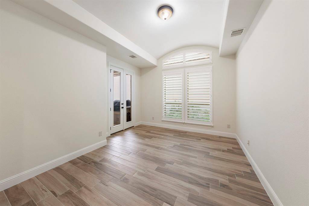 With vaulted ceilings, patio access, and large windows with plantation shutters, the study offers an ideal work-from-home space. This photo has been virtually staged.