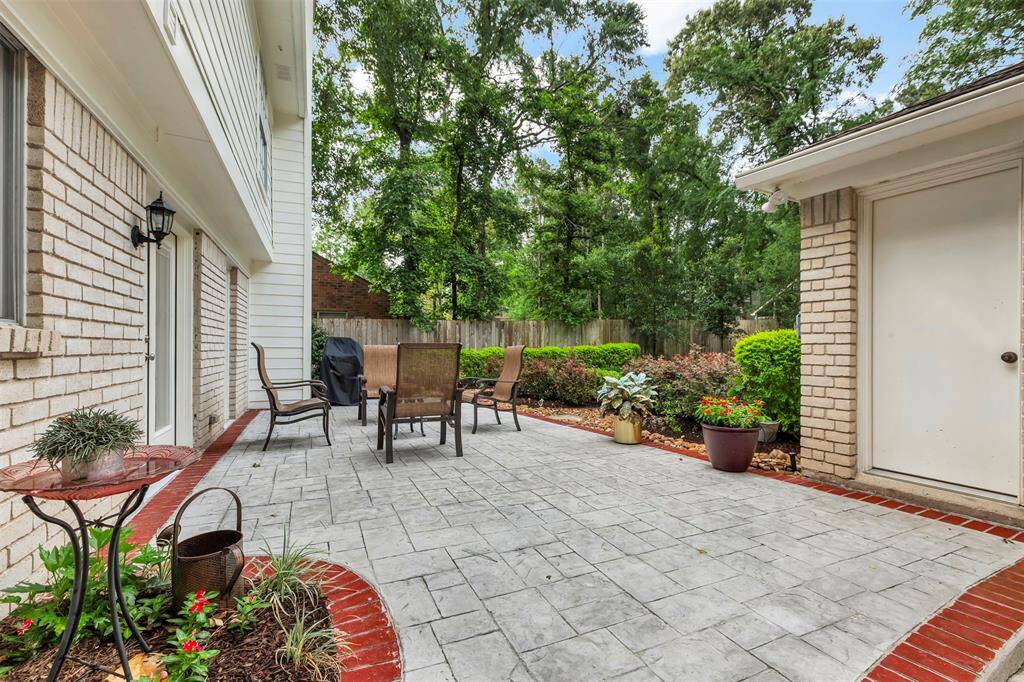 Large patio area with stylish stamped concrete patio, lush greenery, and ample space for outdoor dining and relaxation. Perfect for entertaining!