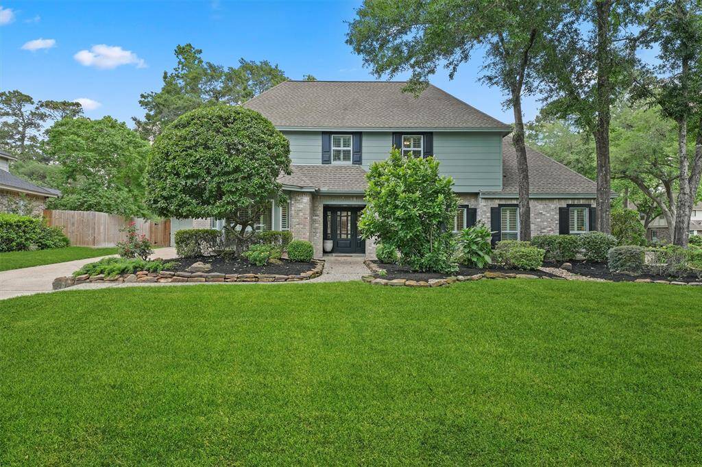 This home features a charming two-story design with a well-maintained front yard and mature trees. The exterior has a mix of brick and siding, complemented by lush landscaping and a welcoming walkway leading to the front entrance. Ideal for buyers seeking curb appeal and a serene setting.