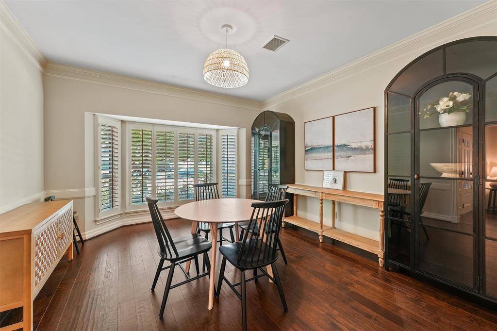 Bright dining room features a large bay window with plantation shutters and a stylish chandelier. Neutral wall colors add a modern touch.