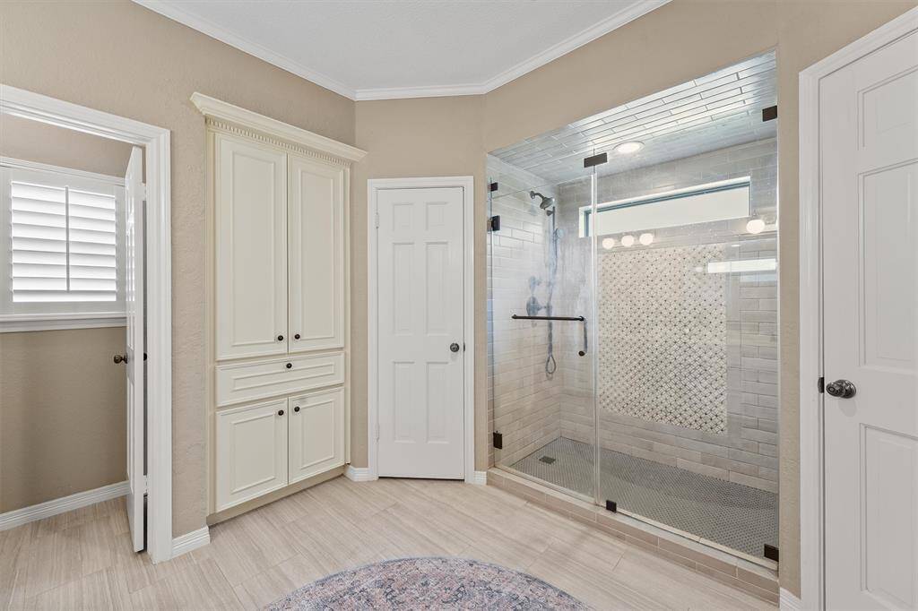 Renovated primary bath featuring frameless shower enclosure and elegant designer tile