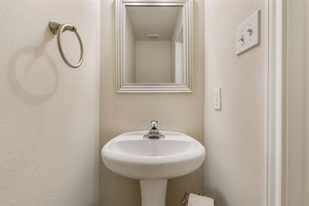 The powder bath is located off the main entry with pedestal sink, decorative mirror and tile flooring.