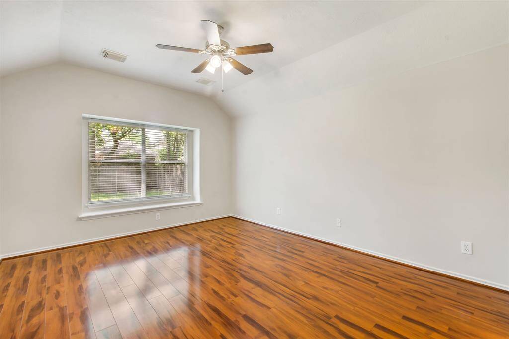 The primary suite features vaulted ceilings, laminate wood floors, a ceiling fan and fresh paint.