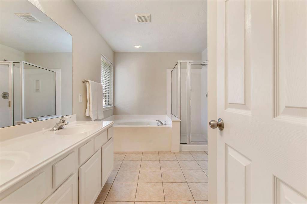 The primary bath presents his and her sinks, a jetted tub and a walk-in shower.