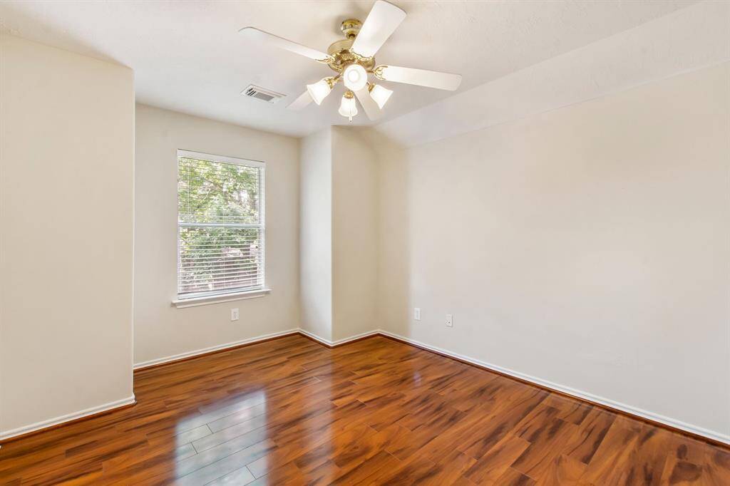 The sizable secondary bedroom #1 has a walk-in closet, laminate wood flooring, fresh paint and a ceiling fan.