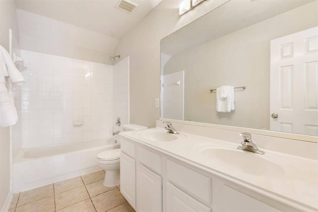 The full secondary bath offers a double sink vanity with cultured marble counters, a shower and tub combination and tile flooring.