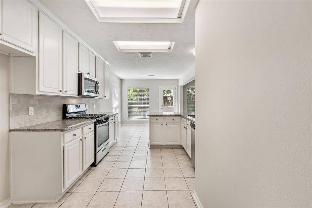 The updated kitchen features stainless steel appliances, granite counter tops, a farmhouse sink andnickel hardware and a tile backsplash.
