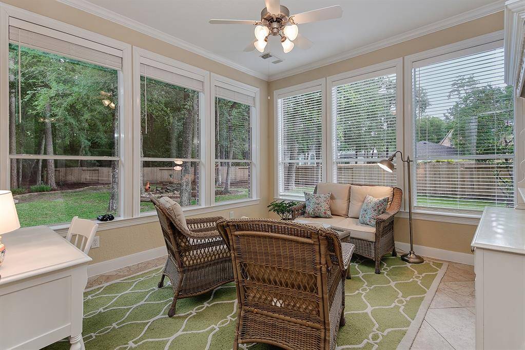 This inviting sunroom features large windows with views of a lush backyard, creating a bright and relaxing space for enjoying nature.