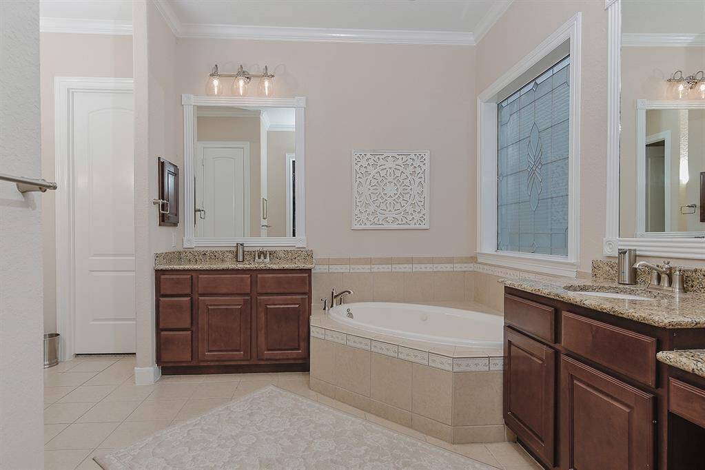The primary bathroom features a lovely corner garden soaking tub, dual vanities and large window for natural light.
