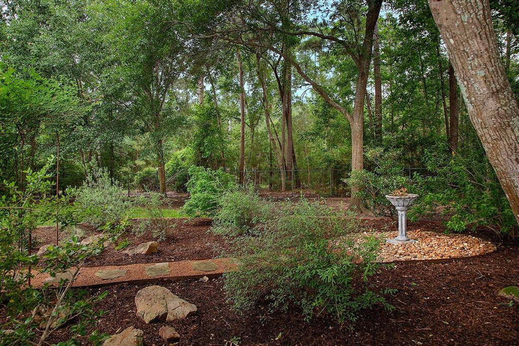 A stone pathway leads to a decorative birdbath, creating a peaceful retreat for nature lovers.