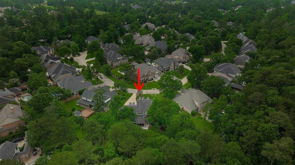 This aerial photo shows house nestled in a lush, tree-filled neighborhood.