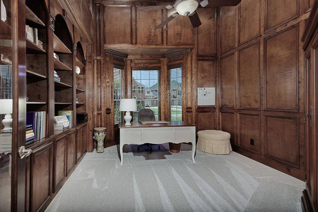 This private home office features rich wood paneling and built-in bookshelves, offering a warm and sophisticated atmosphere.