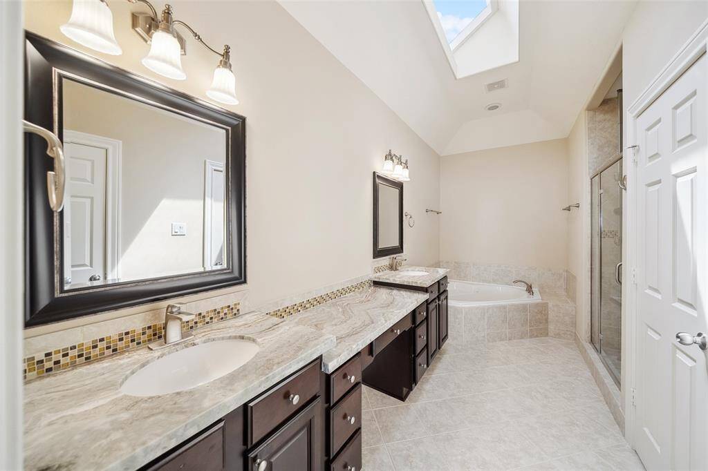 The primary bathroom has updated granite counters and sinks, a jetted tub, and standalone shower. Not pictured is water closet with upgraded toilet.