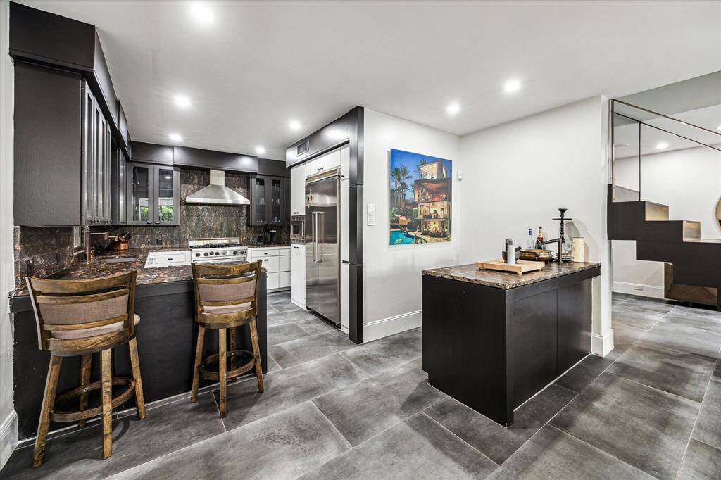 This modern kitchen is outfitted with sleek stainless steel appliances and luxurious Leathered Granite countertops. The combination of stainless steel appliances and Leathered Granite countertops in this kitchen creates a harmonious blend of modern aesthetics and timeless elegance, making it a functional and visually captivating space for cooking and entertaining.