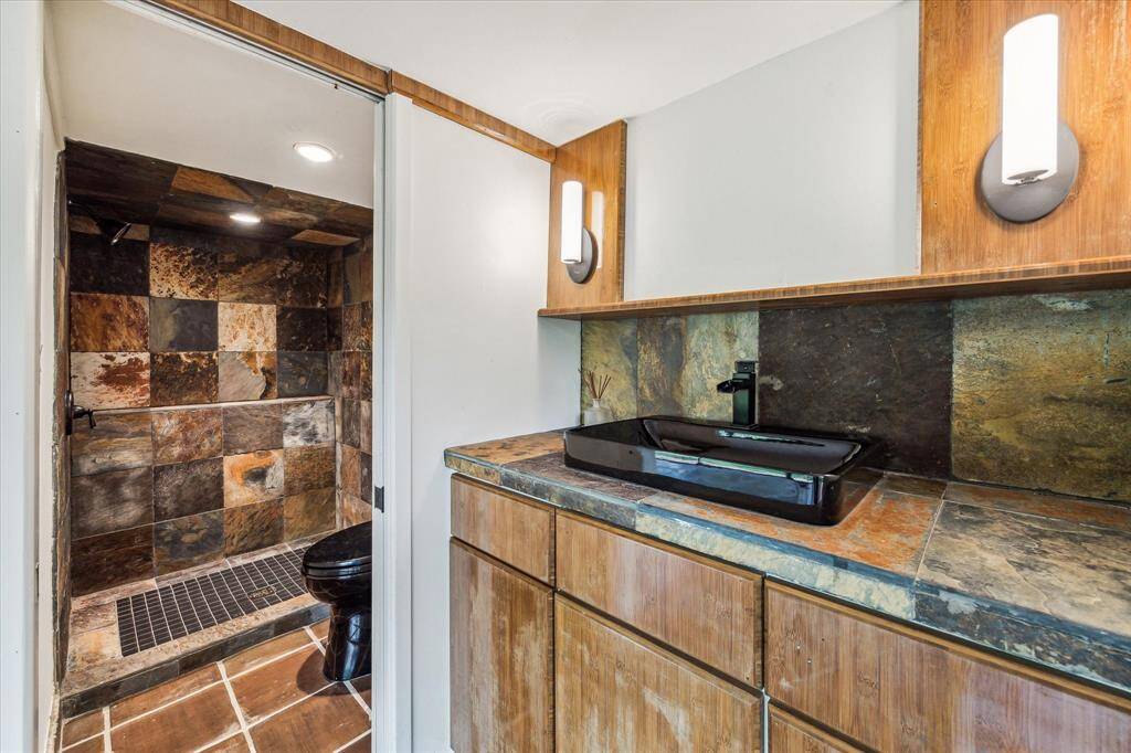 The bathroom boasts a spacious shower with modern fixtures and elegant tile work, providing a rejuvenating experience for guests. A large vanity with ample storage space and a well-lit mirror creates a functional yet stylish area for grooming.