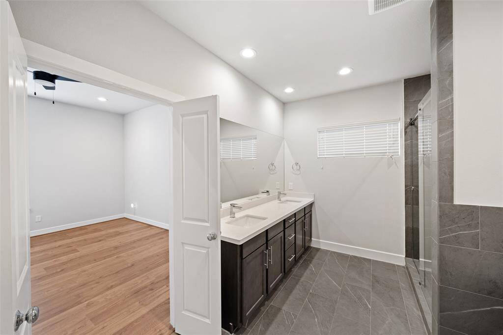 A modern bathroom featuring a sleek freestanding tub and a glass-enclosed shower. The space is accented with grey tiles and recessed lighting, creating a clean and contemporary look.