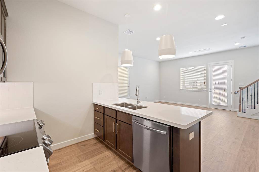 Spacious island with a sink, stainless steel appliances, and ample cabinetry. The open layout flows into a bright living area providing plenty of natural light.