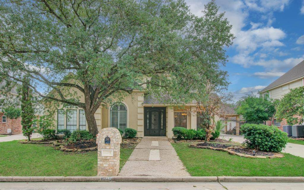 Charming two-story home with a welcoming façade, featuring a large tree and well-maintained landscaping. The driveway leads to a classic front entrance with elegant windows. Ideal for buyers seeking curb appeal and a serene setting.