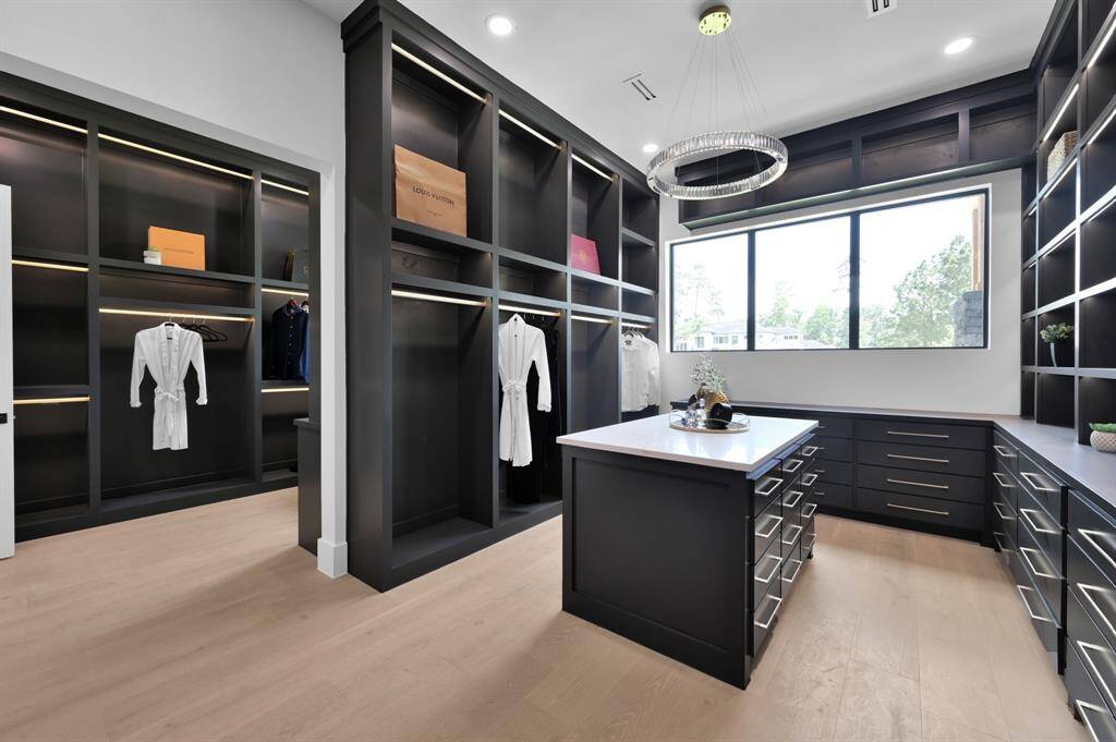 Well appointed primary closet with custom cabinetry and built in lighting