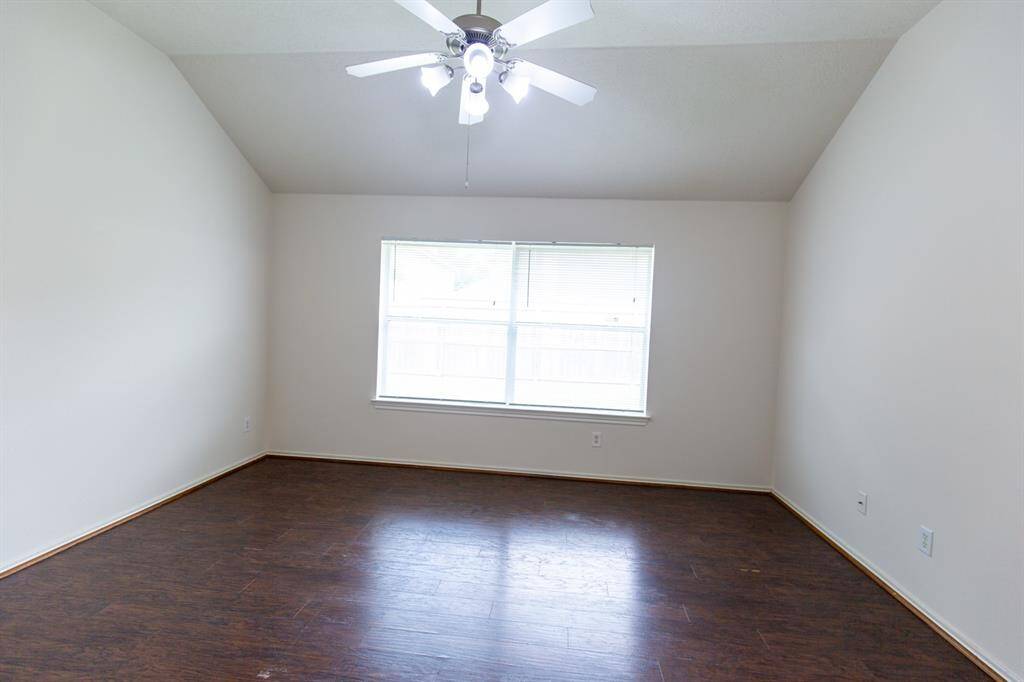 Bright, spacious room with dark wood flooring, a large window for natural light