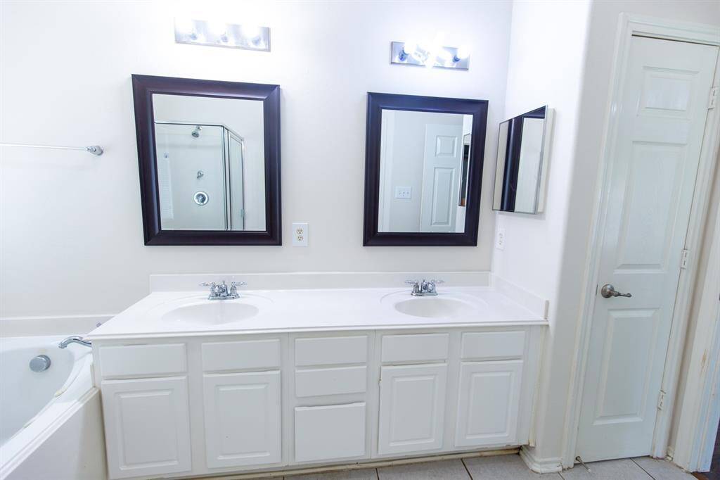 The master bathroom has a separate bathtub and a shower along with light tiled flooring and a neutral color scheme.