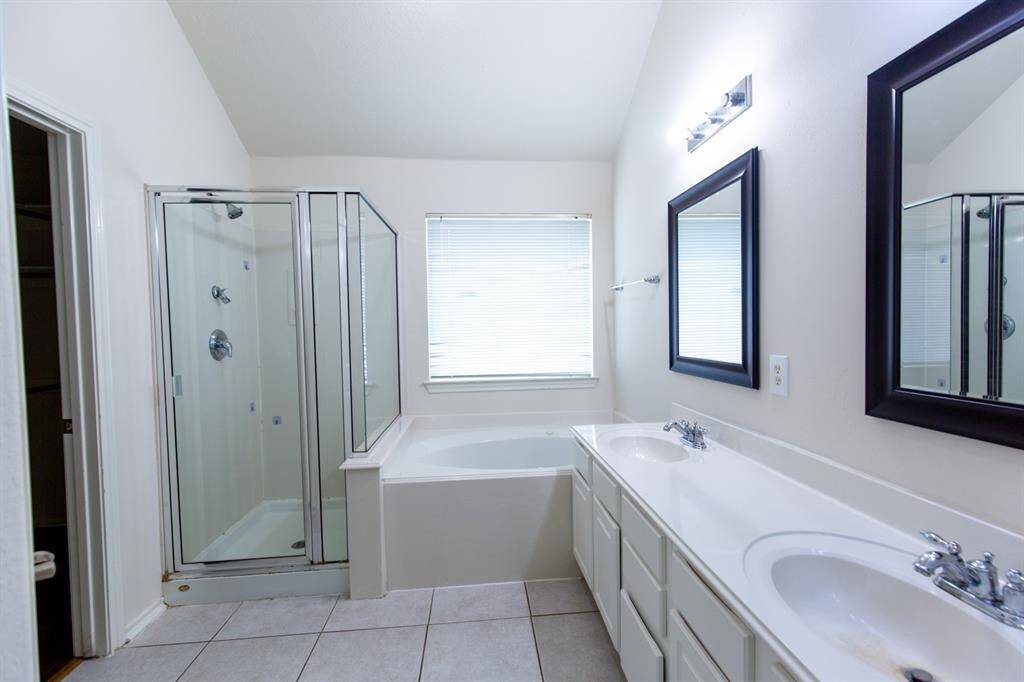 This bathroom features a double vanity with white cabinetry, two framed mirrors, and modern lighting.