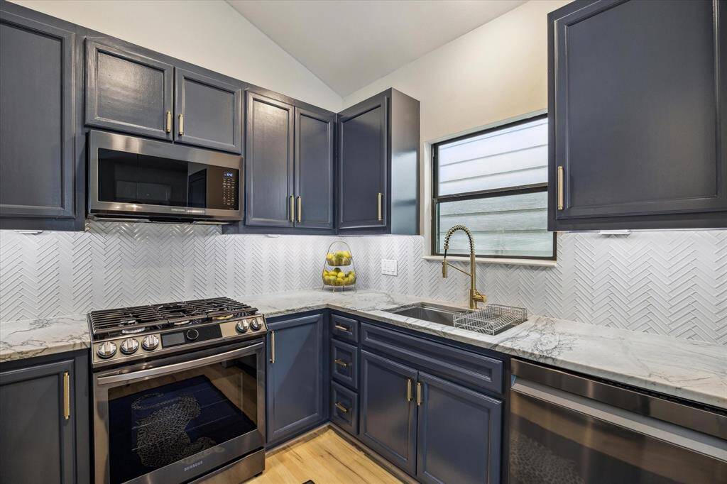 Kitchen features a window at the sink, backsplash, and under cabinet lighting.