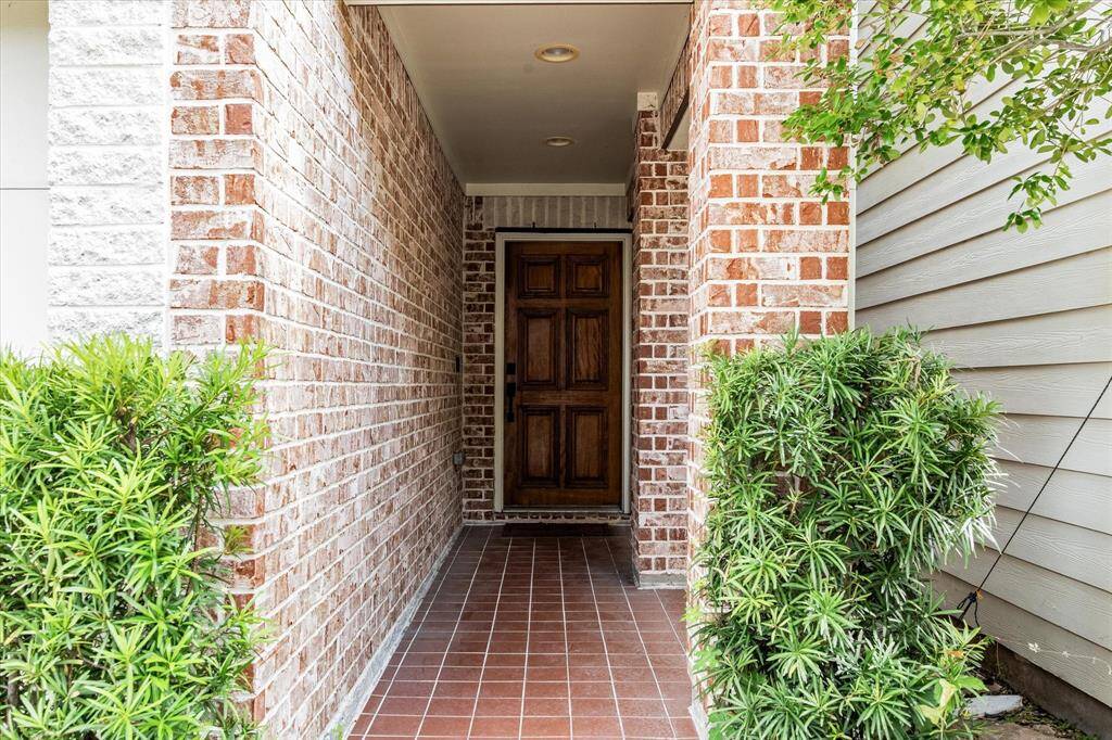 Paved entrance with front landscaping and solid wood door.