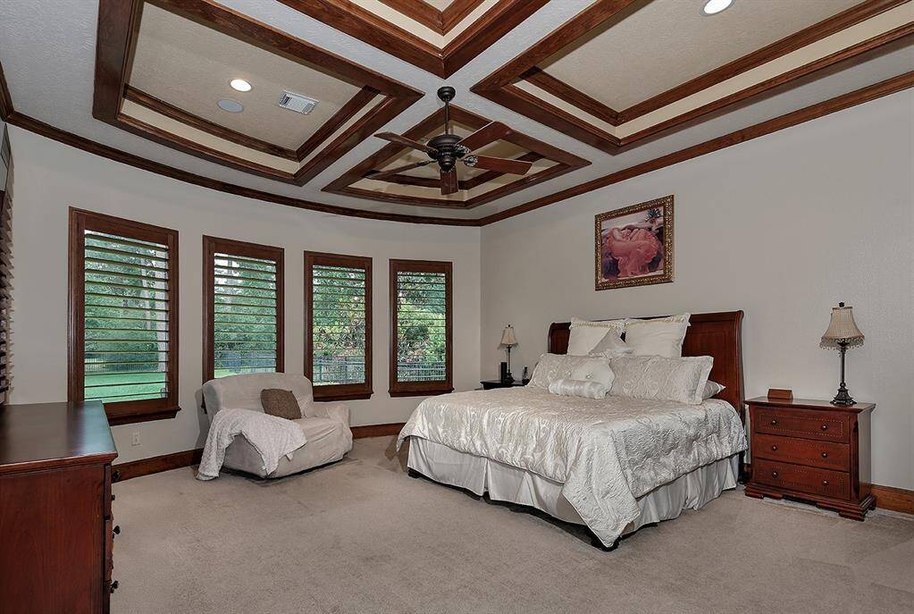 This spacious main level primary suite features elegant coffered ceilings with wood trim accents and many large windows offering amazing views