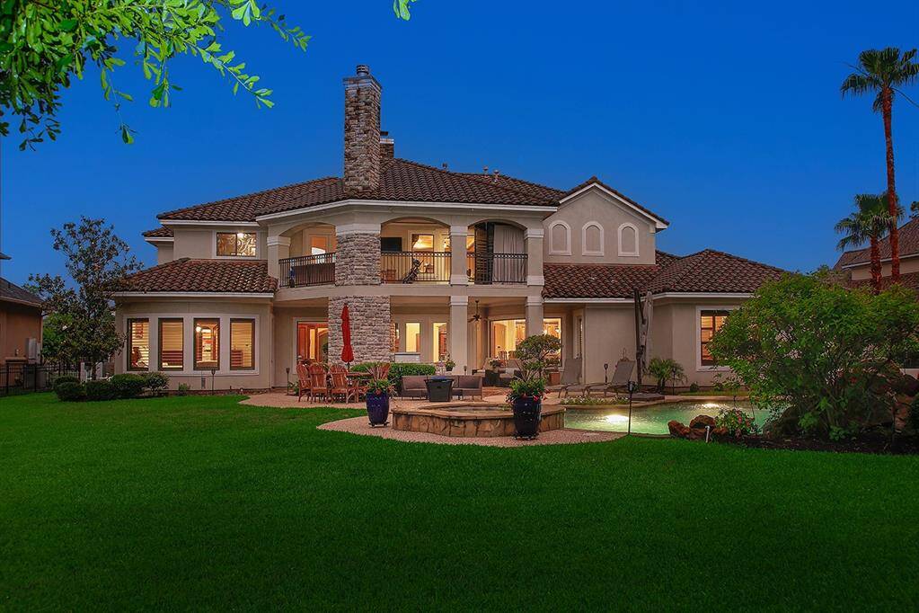 Resort style backyard features a stunning pool with a rock waterfall, surrounded by scenic views and mature trees. The perfect space for relaxation, gathering and entertaining.