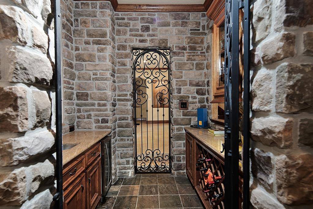 Wine grotto features rustic stone walls, rich wood cabinetry, and combines charm and functionality.