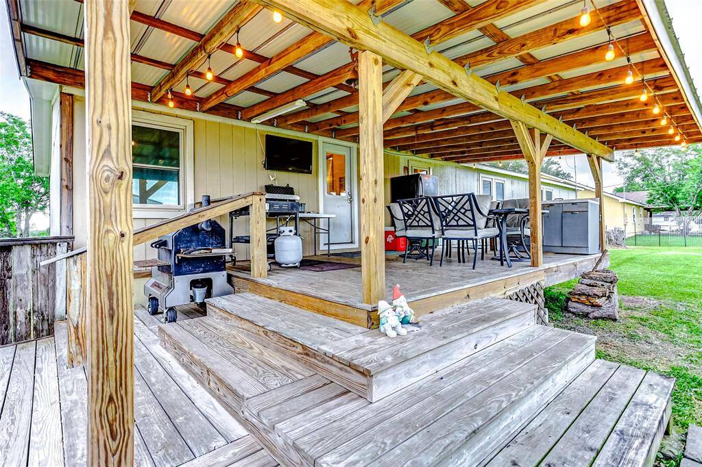 Well designed covered wooden deck with expanded corner steps.