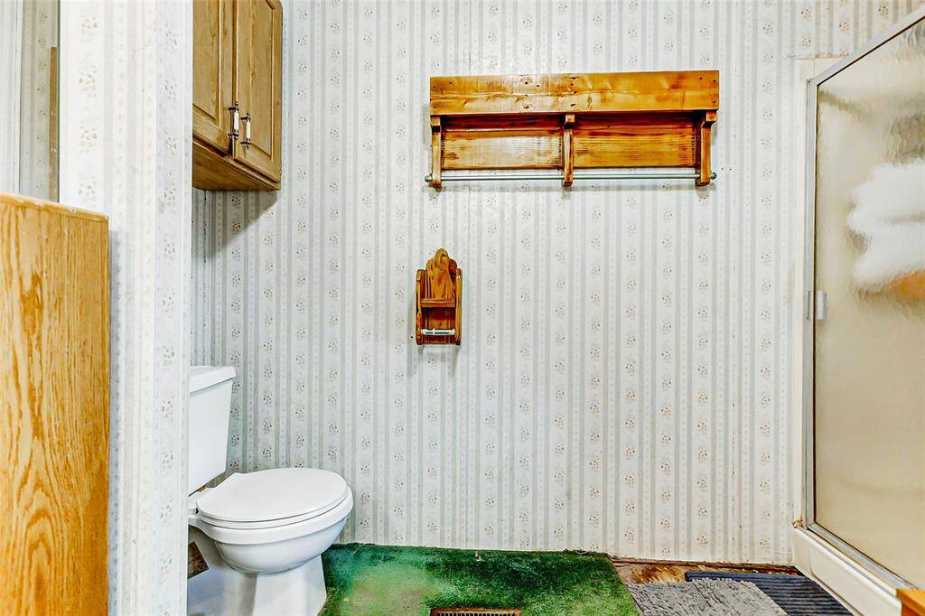 Separate shower, cabinetry & wooden wall shelf for additional storage in this primary bathroom.