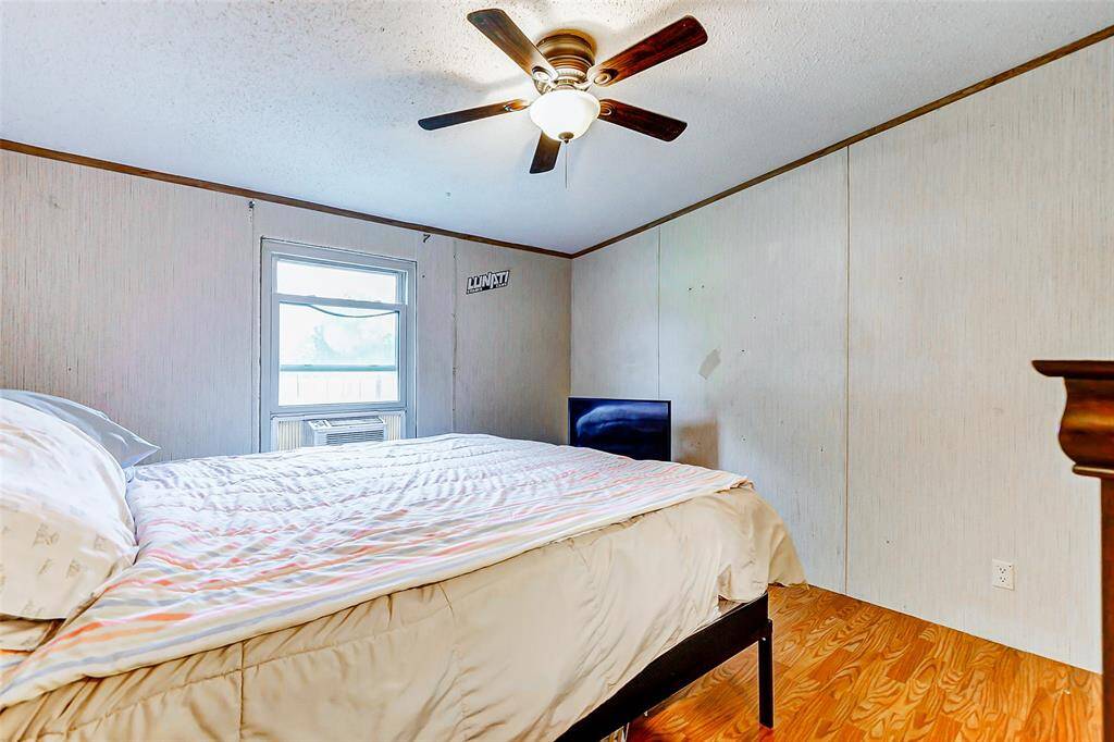 Secondary bedroom with natural light, ceiling fan & window air conditioning.