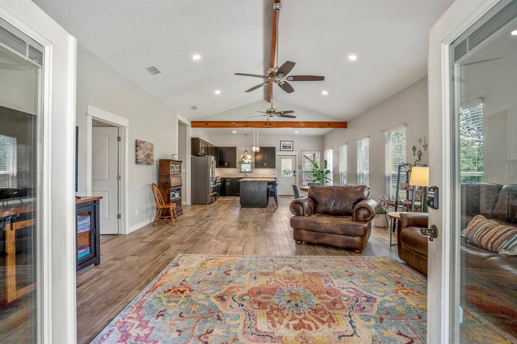 You will love the open floor plan with high ceilings, exposed beams, and large windows for natural light. It includes a cozy seating area overlooking the gorgeous property.