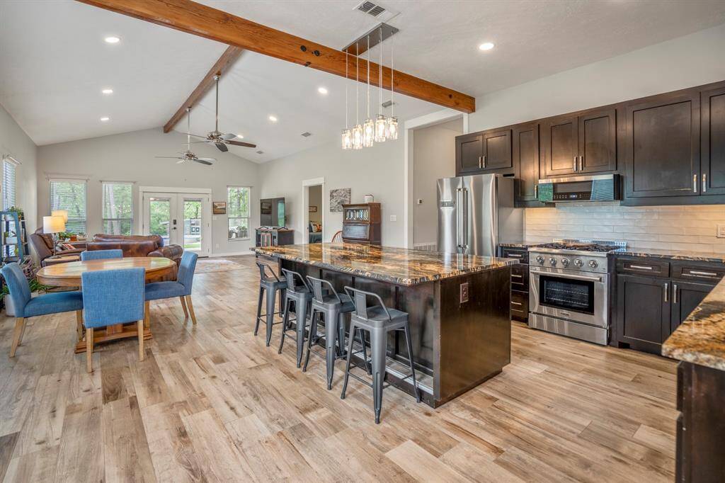A modern kitchen with stainless steel appliances, a large island with bar seating, and dark wood cabinets. The spacious kitchen island with bar seating seamlessly integrates with the dining and living areas, creating a welcoming environment for entertaining.