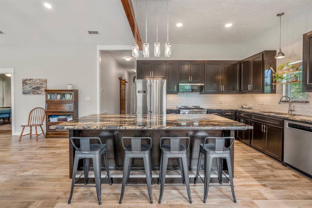 Stainless steel appliances, and stylish pendant lighting add to the charm of this home. The open layout and hardwood floors create a spacious and inviting atmosphere.